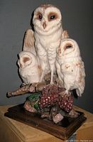 Front and side views of the detailed owl family sculpture showing the three white owls perched with pinecones and realistic carving.