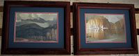 Pair of signed AJ Casson prints with oak wood frames, showing two landscape scenes with matted borders in blue and red.
