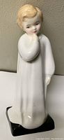 Front view of Royal Doulton 1985 Charles Vase Darling figurine showing the child in white nightgown with hand near mouth, standing on black base.