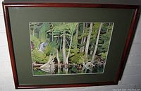 Wide angle photo of wood framed art print showing full frame and mat with artwork titled "Blue Heron" by AJ Casson featuring a blue heron bird, trees and water.