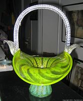 Photo showing front and top view of vintage vaseline glass brides basket with translucent yellow-green swirling glass and clear twisted handle and accents.