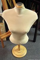 Front view of vintage tailor's dress form showing cream fabric torso on wooden base