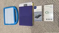 Blue iPad cover with handle, purple foldable iPad cover in packaging, two boxes of tempered glass screen protectors.