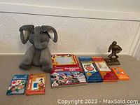Gray Baby Gund Flappy The Elephant plush toy with large ears and trunk sitting on a surface with four educational card sets and a small football player figurine.