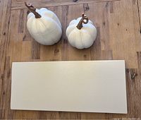 One photo showing the three items: the white floating shelf and two ceramic tapered pumpkins with brown stems on a wooden floor.