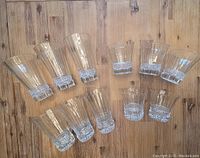 Eleven glasses in total, six taller 16oz glasses and five shorter 8oz glasses, arranged on wooden surface to show size difference and clear crystal pattern.