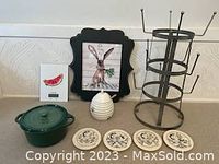 Photo showing green Parini enamel bakeware with lid, ceramic honey pot with wooden dipper, four decorative ceramic coasters, metal 3-tier mug tree stand, digital kitchen scale with watermelon image, and framed rabbit art.