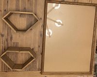 Wooden rectangular frame and two diamond-shaped wooden floating shelves on a wooden surface.