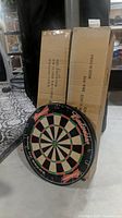 Budweiser themed dart board leaning against boxes in basement environment