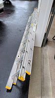 Full view of the folded aluminum extension ladder showing length and structure next to garage door.