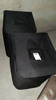 Two black zippered storage bags containing beds and stands