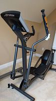 Front left view of the elliptical showing handlebars, console, and foot pedals.
