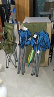 Photo of folded camp chairs, green and blue fabric, metal frames.