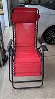 Full view of red outdoor adjustable recliner chair with red mesh seat and backrest, supported by a black metal frame.