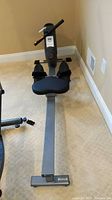 Full view of the Sunny rowing machine showing padded seat, footrests, rail, and digital display on front handlebar.