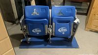 Two blue Super Bowl XLVII stadium seats with Bud Light logo on blue base shown together in basement setting.