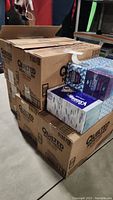 Stacked large cardboard boxes labeled Quilted Northern 3-ply Ultra tissues with some Kleenex tissue boxes on top.