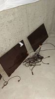 Two flat-screen TVs on floor with cords. One is Samsung and one is Element.