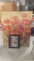 Large canvas print featuring red poppies with a smaller matted cityscape print placed in front.