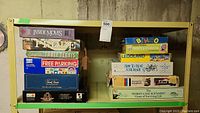 Shelf of assorted vintage board games stacked in two piles showing visible titles