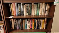 Wide shot of two shelves filled with hardcover novels in clear protective sleeves