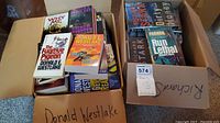 Two cardboard boxes filled with various softcover and hardcover books by Donald Westlake, Richard Stark, and Tim Cocky.