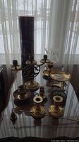Overview of brass candlesticks, zodiac dishes, vases and glass bowl on table