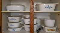 Top shelf showing large plain white rectangular dish with glass lid and large Cornflower Blue casserole