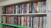 Two shelves tightly packed with assorted DVDs of movies and TV shows spanning various genres and collections.