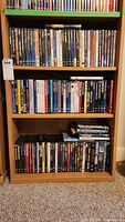 Wide shot of three shelves filled with DVD cases in a wooden bookcase