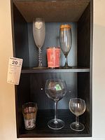 Full view of all six pieces: top shelf holds two champagne flutes and red souvenir glass; bottom shelf holds large and small wine glasses and vintage juice glass.