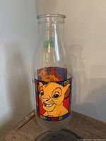 Full view of clear glass bottle with colorful cartoon images of Simba on front.