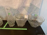 Three pressed glass pieces including a tall vase, a medium square bowl, and a large footed bowl with scalloped edges