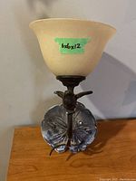 Front view of metal wall light showing glass shade with measurement label and metal bird detail on mounting arm.