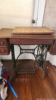 Front view of the wooden-cabinet antique Singer sewing machine with treadle base.