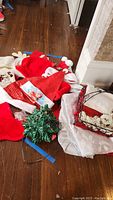 Overview of Christmas decorations including ceramic tree, Santa hats, stockings, and metal basket on floor