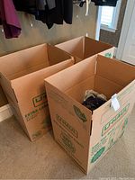 Three large U-Haul boxes, two empty and one containing clothing at the bottom