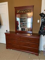 Front view of cherry wood dresser with attached mirror showing drawer configuration and mirror design.