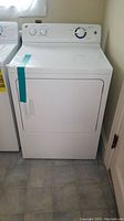 Front view of white GE clothes dryer with front door and control panel visible.