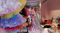 Photo of hanging tutu skirts and various dresses on hangers.
