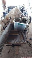 Spring-loaded dinghy hull interior piled with sails, rope, fenders, and storage bin