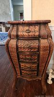 Front view of the Bombay style 5-drawer wicker storage chest showing curved drawers and metal ring handles.