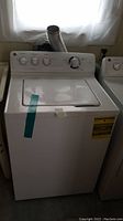 Front view of GE top-load washer showing control panel, lid and surrounding area