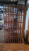 Front view of two upright wooden wine racks against basement wall, showing full grid of bottle slots.
