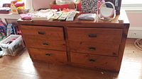 Frontal view of the wood dresser with six drawers, showing metal recessed handles and some scratches on the wood surface.