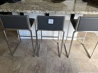 Three stools side by side at kitchen counter, showing front view and overall design