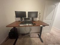 Front view of standing desk with dual monitor setup and keyboard on surface
