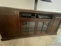Entertainment console front view showing the four-door setup with equipment inside and the glass paneled doors in the center.
