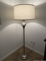 Full view of the floor lamp showing its tall metal stand with brushed nickel finish and eggshell fabric shade.
