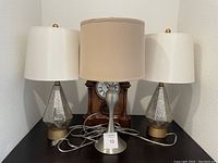 Front view showing all three lamps on a black surface with a clock in background